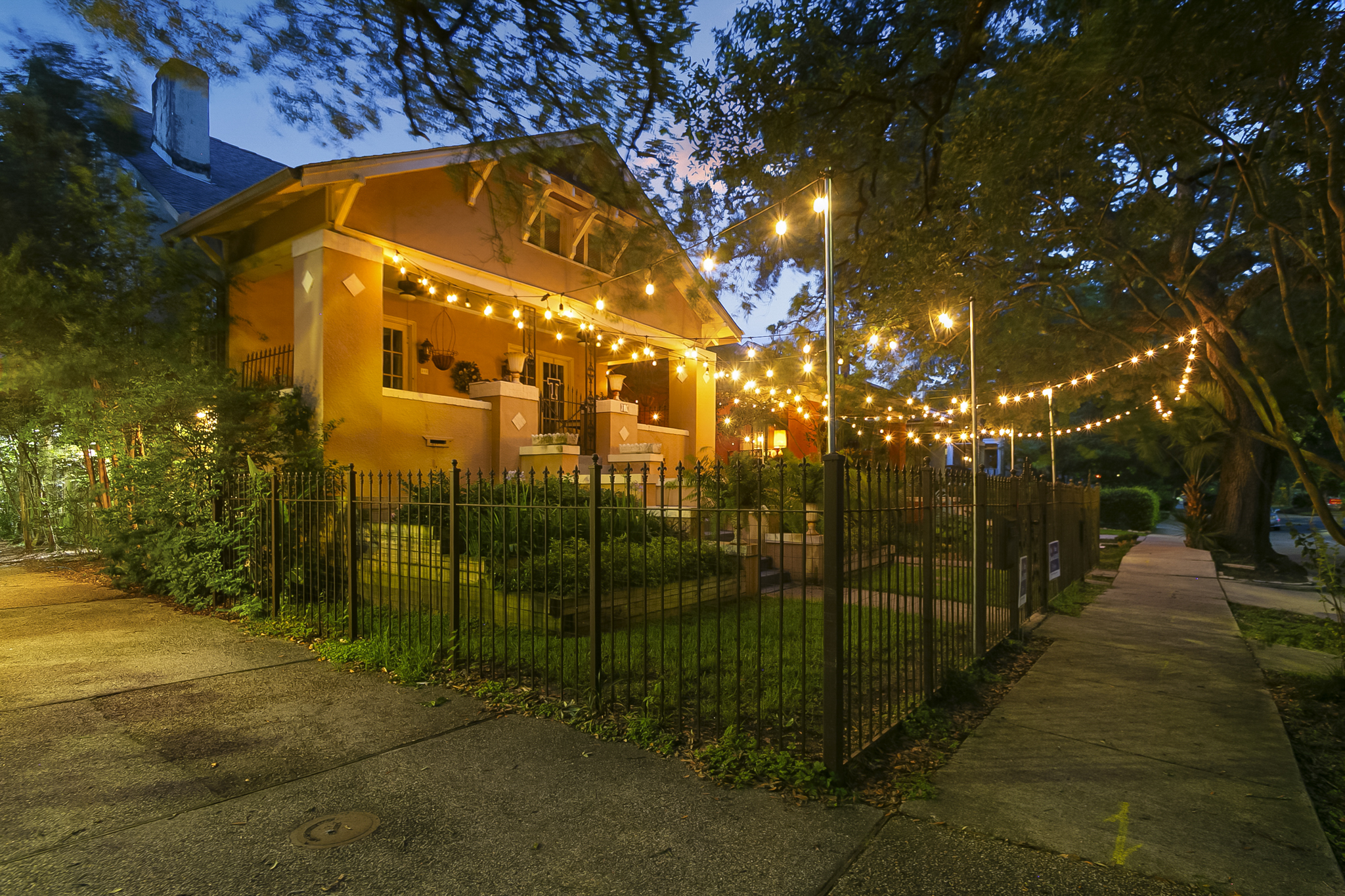 New Orleans craftsman home glowing under string lights at dusk