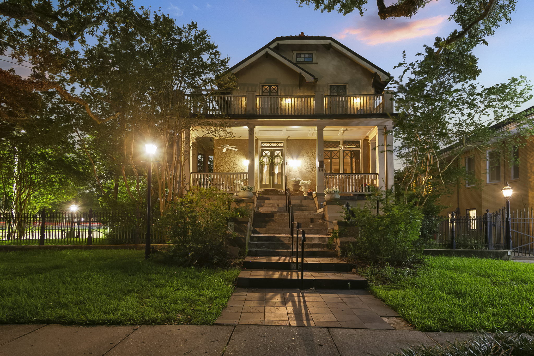 Historic New Orleans craftsman home with a lit front porch at twilight